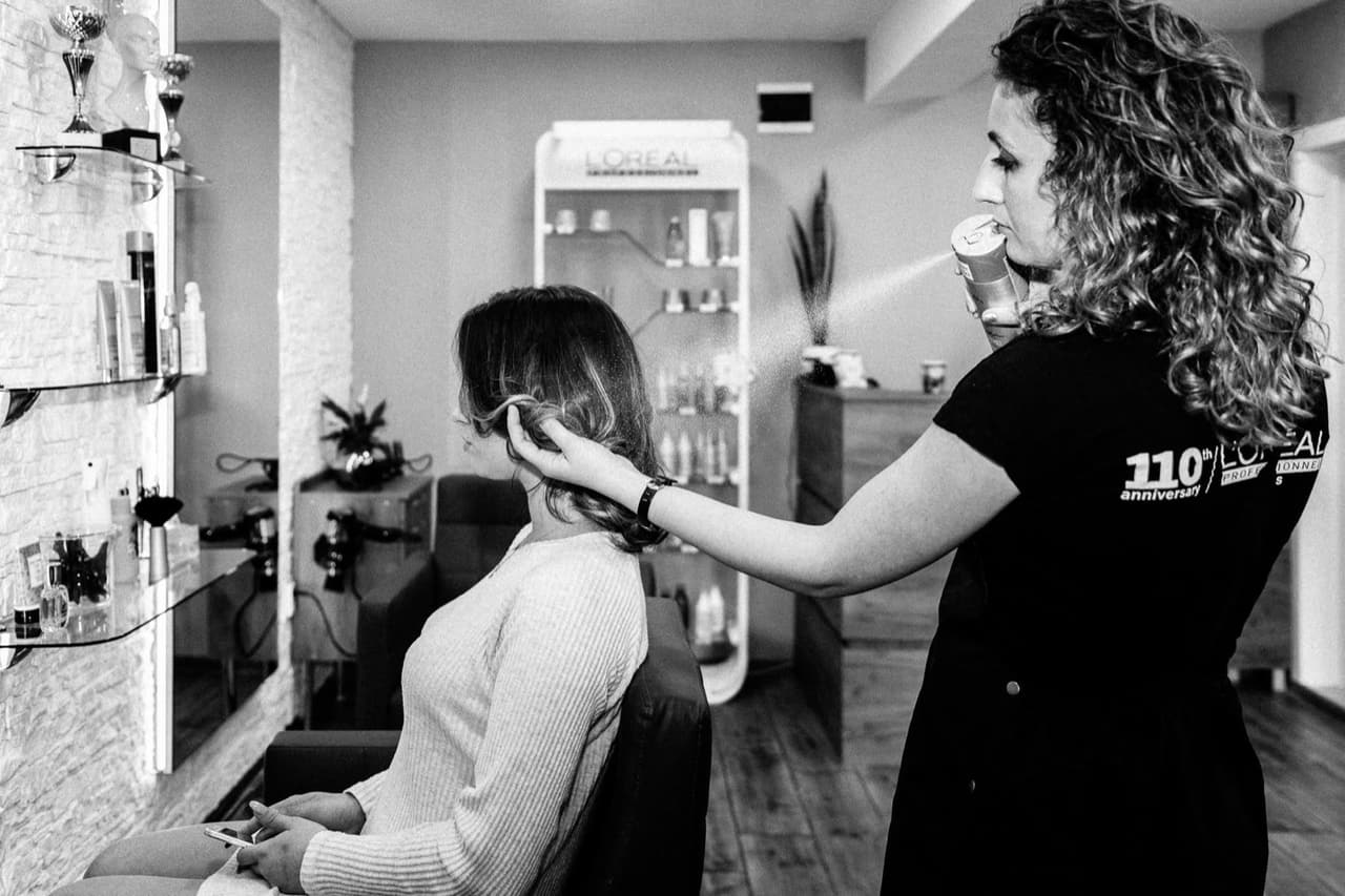 Ваня оформя косата на клиентка в салон VANIS в Бургас, до рафт с продукти L'Oréal Professionnel